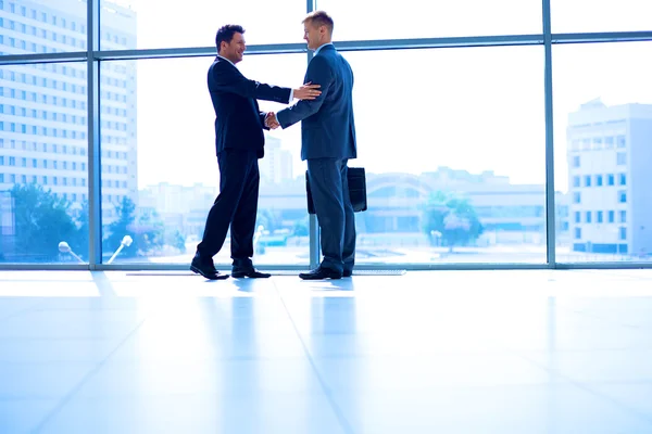 Full length image of two successful business men shaking hands with each other