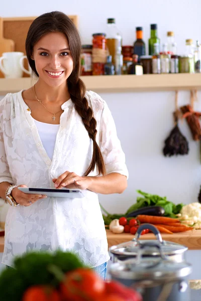 Jeune femme utilisant une tablette informatique pour cuisiner dans sa cuisine — Photo