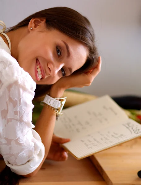 Jonge vrouw die kookboek leest in de keuken, op zoek naar recept — Stockfoto