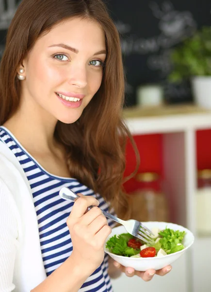 Giovane donna mangiare insalata e tenere un'insalata mista — Foto Stock