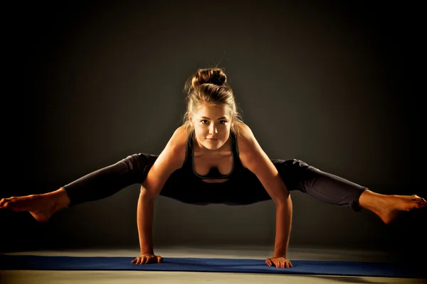 Giovane donna che fa esercizio di yoga sul tappeto — Foto Stock