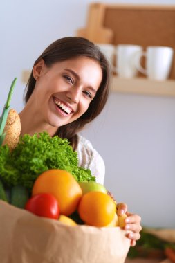 Elinde sebzeli alışveriş torbası tutan genç bir kadın.