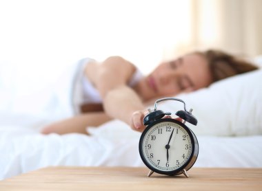 Evdeki yatak odasında uyuyan genç kadın ve çalar saat.