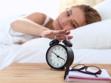 Evdeki yatak odasında uyuyan genç kadın ve çalar saat.