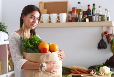 Elinde sebzeli alışveriş torbası tutan genç bir kadın.