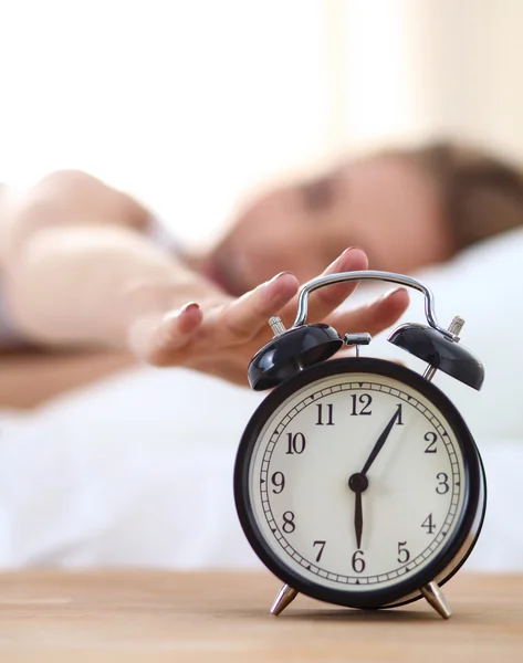 Joven mujer dormida y despertador en el dormitorio en casa —  Fotos de Stock