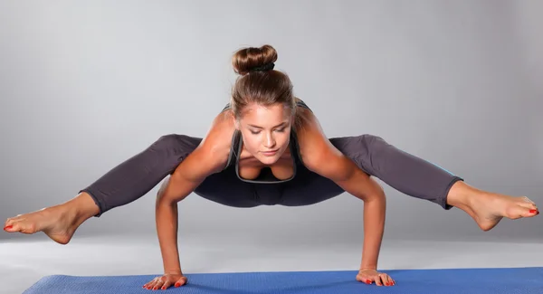 Young woman doing yoga exercise on gray background — Stock Photo, Image