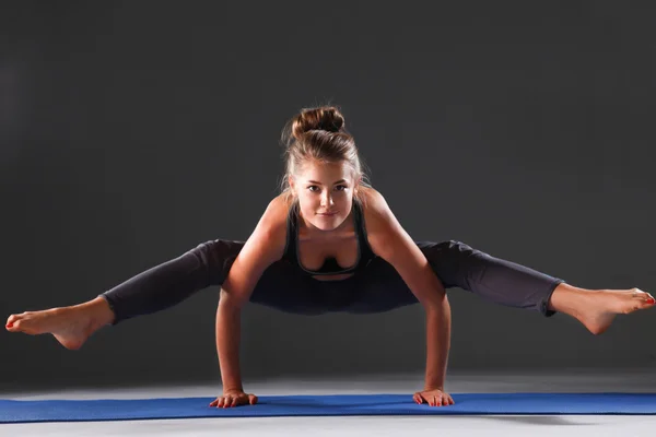 Young woman doing yoga exercise on mat — Stock Photo, Image