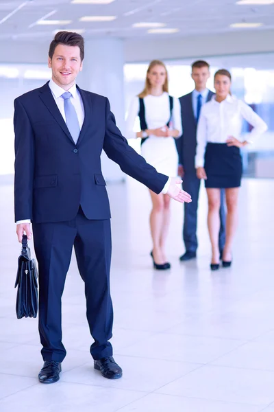 Portret van jonge zakenman in kantoor met collega's op de achtergrond — Stockfoto