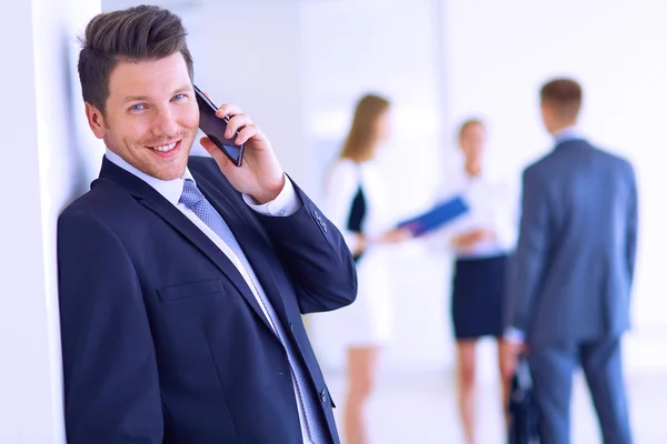 Portret van jonge zakenman in kantoor met collega's op de achtergrond — Stockfoto