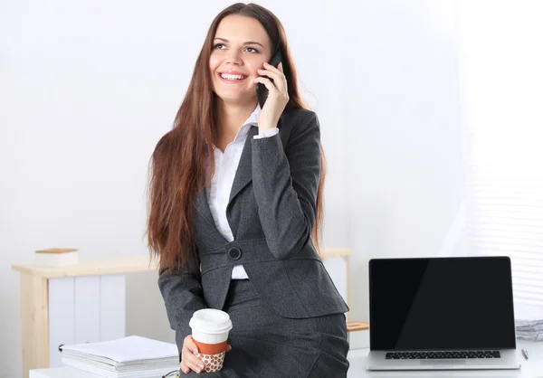 Femme d'affaires souriante parlant au téléphone au bureau — Photo