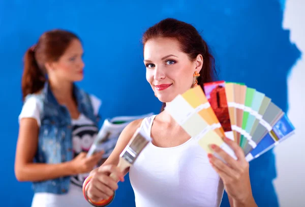 Duas mulheres bonitas jovens segurando paleta de cores, de pé perto da parede . — Fotografia de Stock