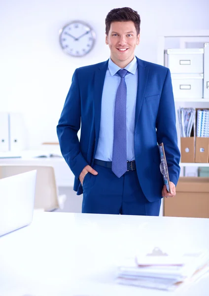 Zakenman of manager die op kantoor tegen zijn bureau staat — Stockfoto