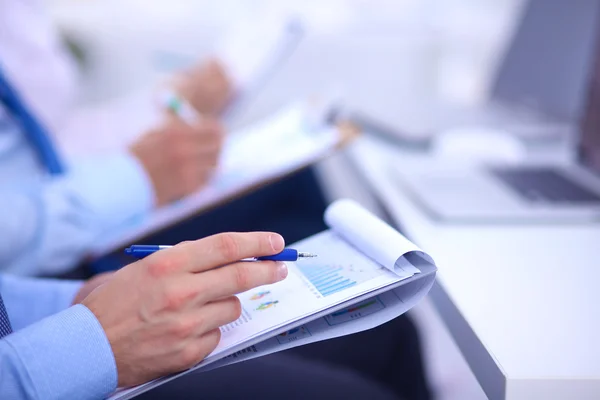 Zakenmensen zitten en schrijven op zakelijke bijeenkomst, in functie — Stockfoto