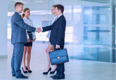 İki başarılı iş adamının el sıkışırken tam boy görüntüsü.