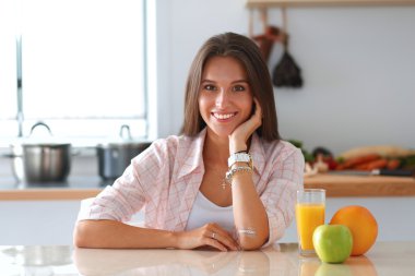 Genç bayan mutfakta masanın yanında oturuyor.