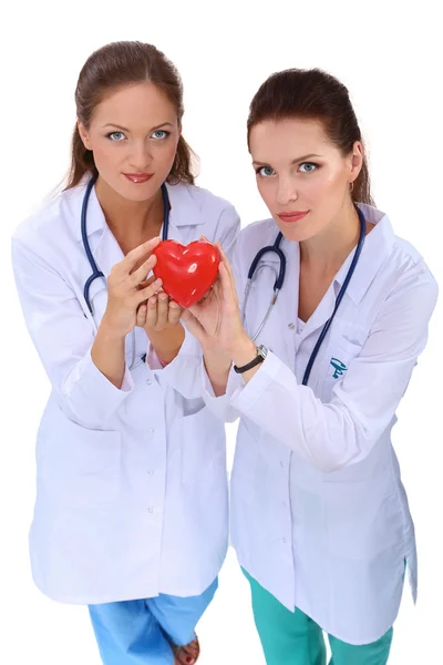 Kırmızı kalp taşıyan iki kadın doktor, beyaz arka planda izole edilmiş. — Stok fotoğraf