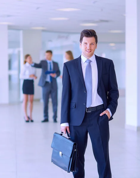 Portret van jonge zakenman in kantoor met collega's op de achtergrond — Stockfoto