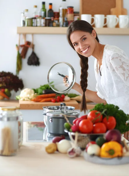 Jeune femme debout près de la cuisinière dans la cuisine — Photo