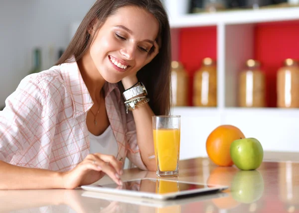 Mujer usando una tableta mientras bebe té en su cocina —  Fotos de Stock