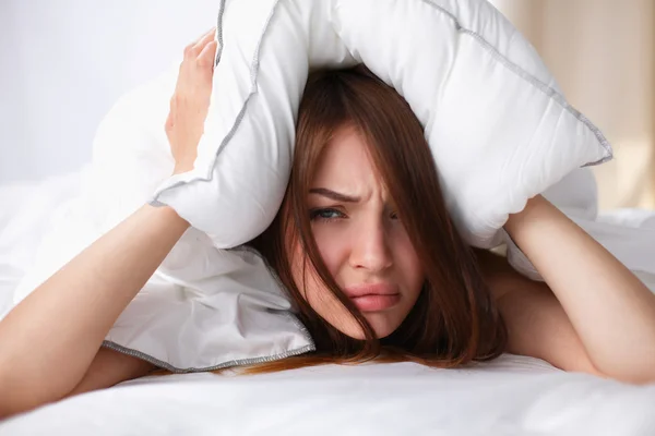 Mujer acostada en la cama y cerrando las orejas con almohada — Foto de Stock