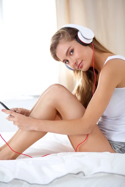 Portret van mooie vrouw in de ochtend luisteren muziek zittend op bed thuis — Stockfoto