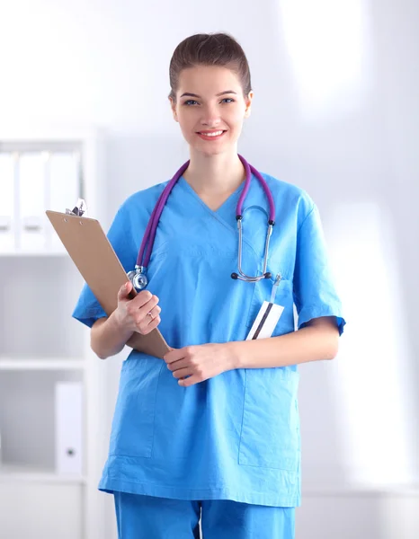 Médecin souriante avec un dossier en uniforme debout à l'hôpital — Photo