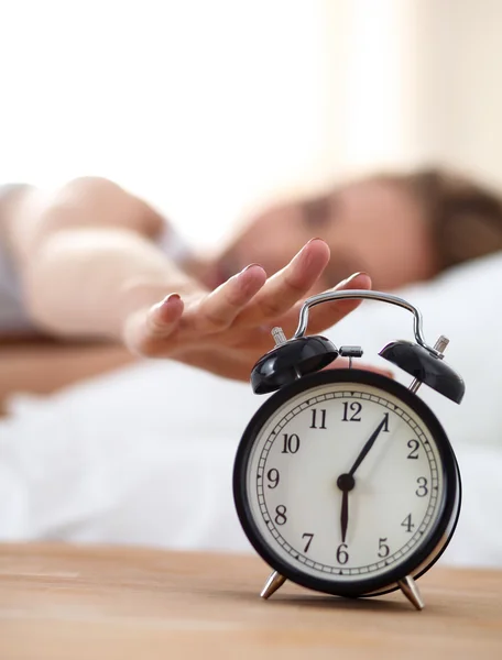 Jeune femme endormie et réveil dans la chambre à coucher à la maison — Photo