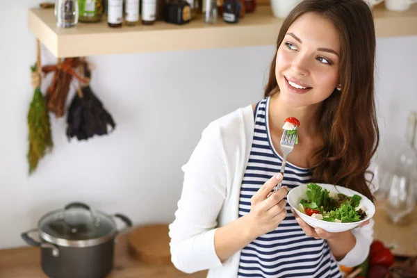 Junge Frau isst Salat und hält einen gemischten Salat in der Hand — Stockfoto