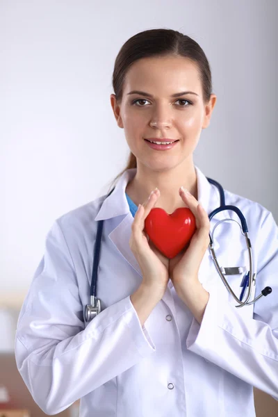 Mujer joven doctora sosteniendo un corazón rojo — Foto de Stock