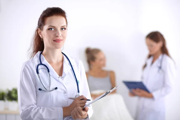 Usmívající se doktorka se složkou v uniformě stojící v nemocnici — Stock fotografie