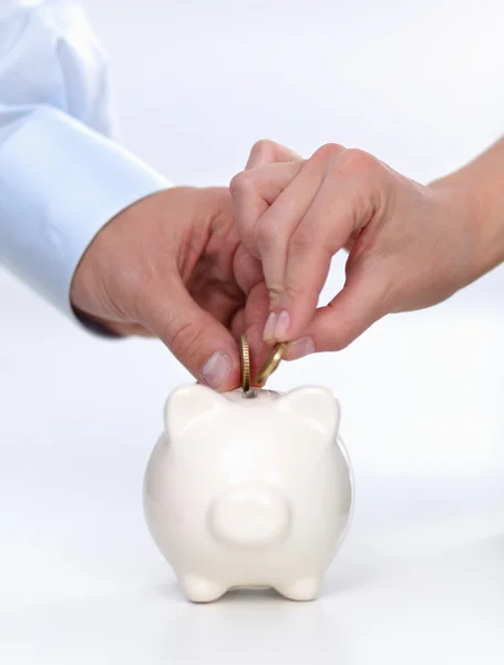 People putting coin into the piggy bank — Stock Photo, Image