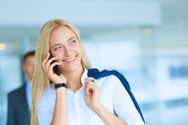 İş kadını ofiste oturan akıllı telefonuyla mesaj gönderiyor.