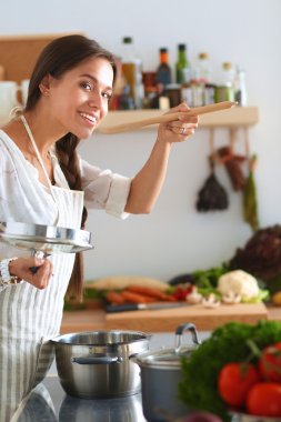 Mutfakta ahşap kaşıkla yemek pişiren kadın