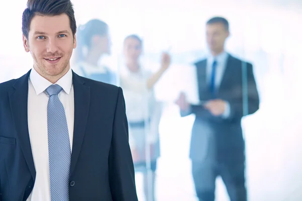 Porträt eines jungen Geschäftsmannes im Amt mit Kollegen im Hintergrund — Stockfoto