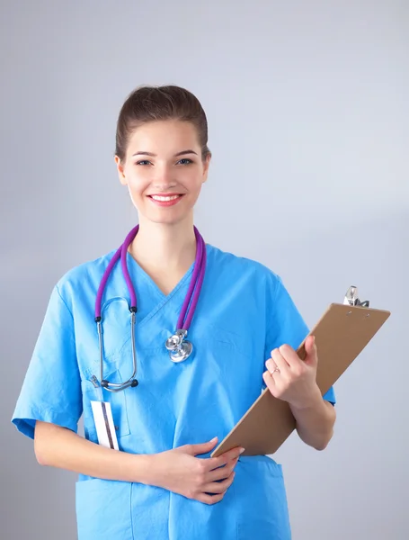 Médecin souriante avec un dossier en uniforme debout à l'hôpital — Photo