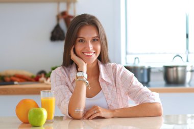 Genç bayan mutfakta masanın yanında oturuyor.