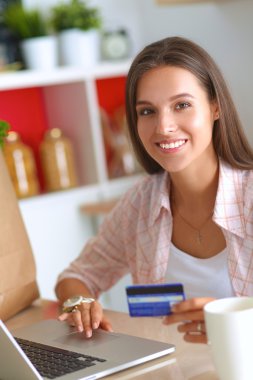 Gülümseyen kadın mutfakta tablet ve kredi kartı kullanarak alışveriş online