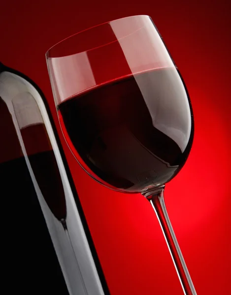 Elegantes Weinglas und eine Weinflasche vor schwarzem Hintergrund. — Stockfoto