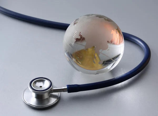 Stetoskop blízko skla Globus mapa světa — Stock fotografie