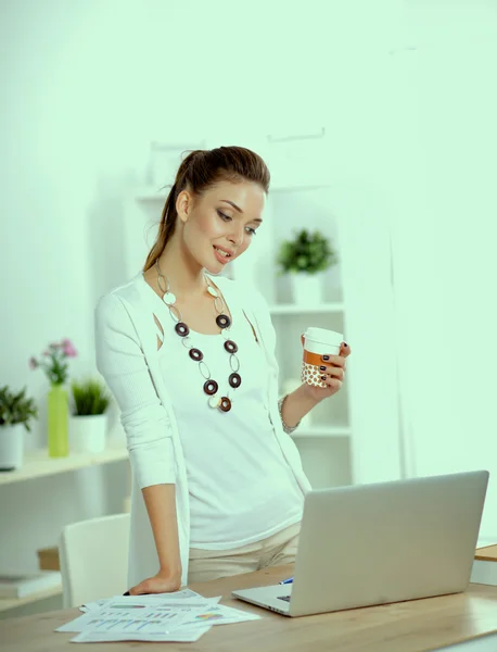Atraktivní mladá podnikatelka stojící u stolu v kanceláři — Stock fotografie