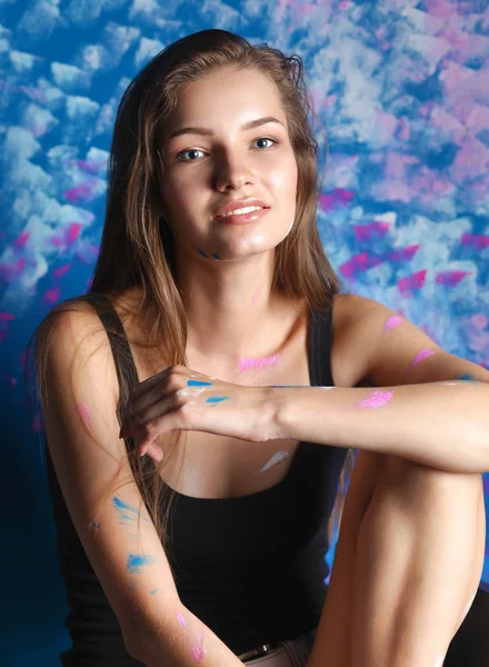 Ung kvinna sitter nära måleri wall — Stockfoto