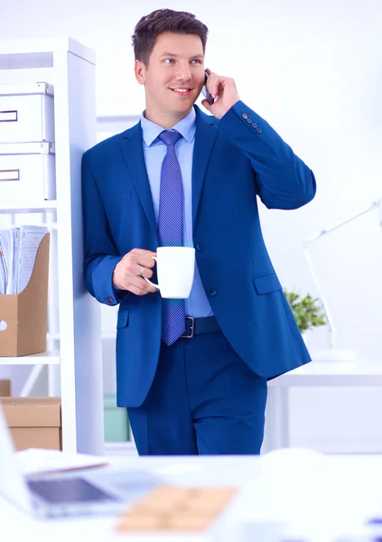 Lachende zakenman permanent en mobiele telefoon gebruiken in office — Stockfoto