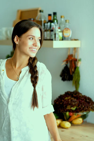 Ung kvinna står nära skrivbord i köket — Stockfoto