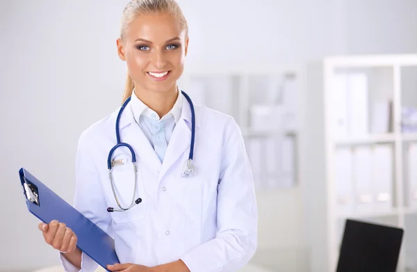 Lächelnde Ärztin mit Ordner in Uniform steht im Krankenhaus — Stockfoto