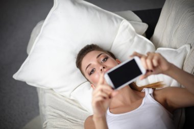 Yatak odasında cep telefonu ile kendini bir fotoğraf çekici mutlu esmer