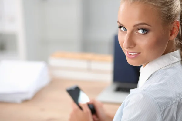 Businesswoman sending message with smartphone sitting in the office — Stock Photo, Image