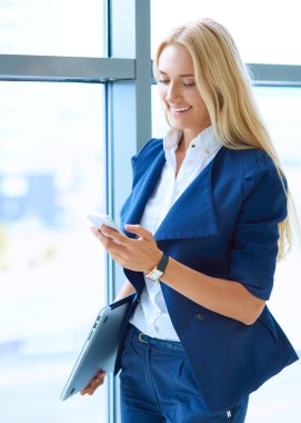 Ofis pencere karşı ayakta işkadını cep telefonunda bir mesaj