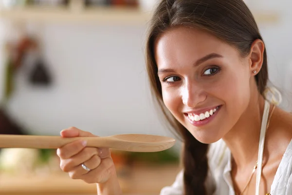 Mujer cocinera en cocina con cuchara de madera —  Fotos de Stock