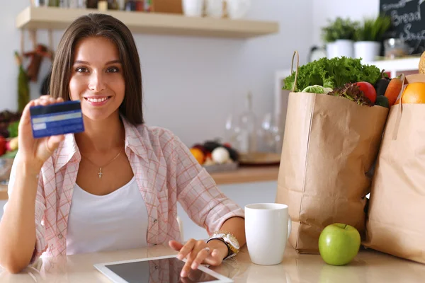 Donna sorridente shopping online con tablet e carta di credito in cucina — Foto Stock